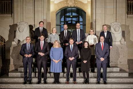 Männer und Frauen posieren für ein Foto auf einer Treppe.